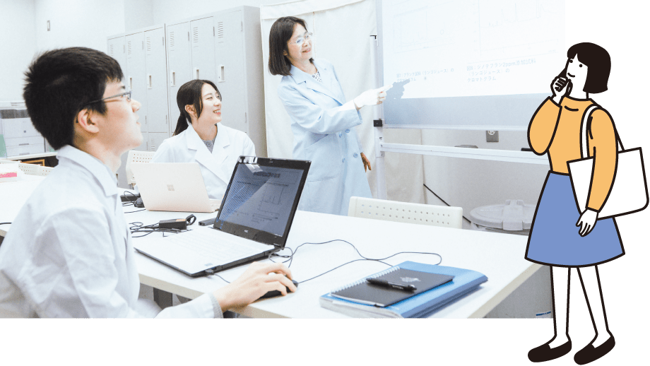 講義室で説明する白衣の女性と学生たち