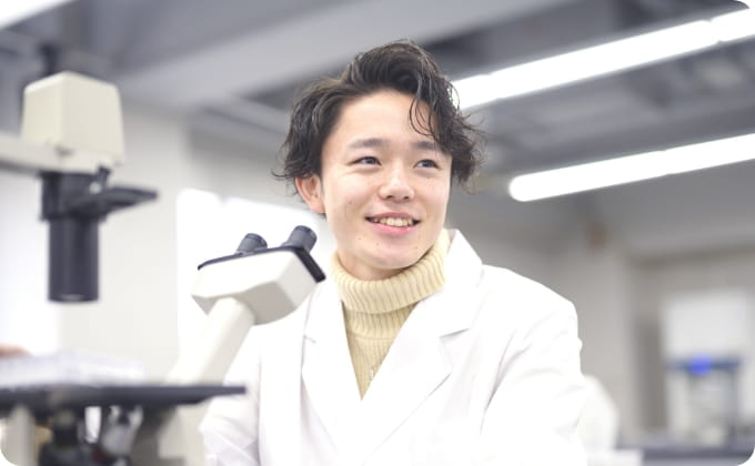 顕微鏡を前に笑顔の学生