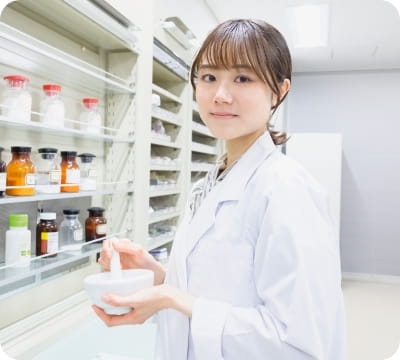 薬棚の前で実習をする白衣姿の学生